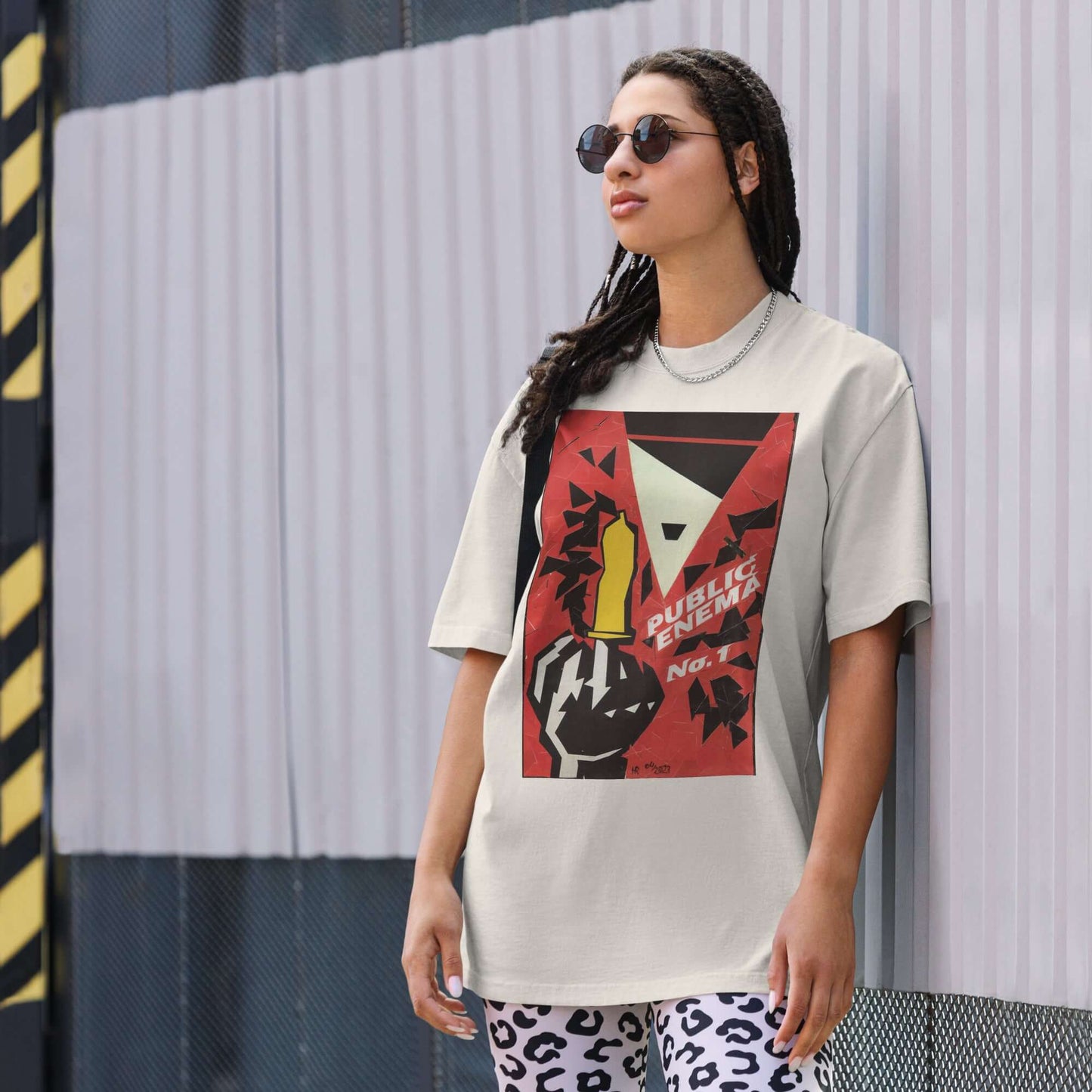 Model wearing oversized PUBLIC ENEMA No. 1 t-shirt with bold protest graphics and a vintage look, styled for impact.